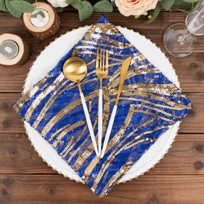 Blue and gold sequin napkin with gold utensils on a plate.