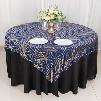 Round table adorned with a blue and gold wave pattern tablecloth and floral centerpiece.