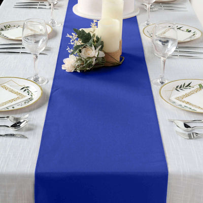 Blue table runner on a dining table set with plates and glasses.