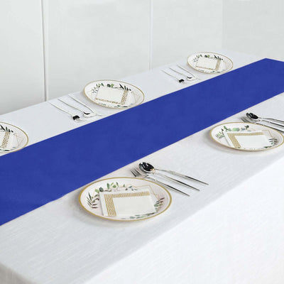 Blue table runner on a dining table set with elegant plates and cutlery.