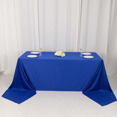 Blue tablecloth draped over a table with decorative floral centerpiece and plates.