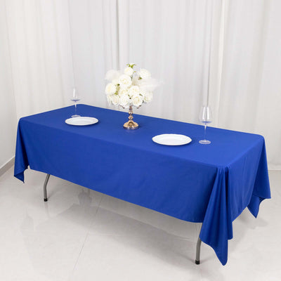Blue tablecloth on a dining table set with plates and wine glasses.