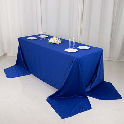 Blue tablecloth draped over a table with plates and glasses arranged on top.