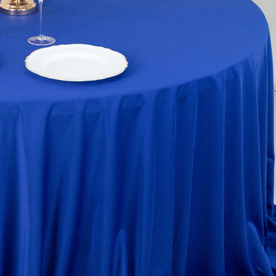 Blue tablecloth draped elegantly over a round table with a white plate on top.