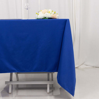 Blue tablecloth draped over a table with a glass and flowers