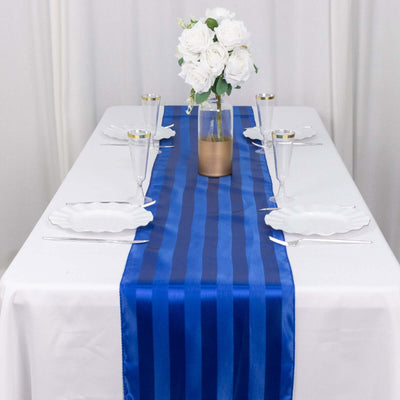 Blue striped table runner on a white table with elegant glassware and floral centerpiece.
