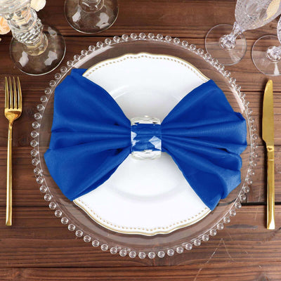 Blue satin bow napkin on an elegant dinner plate with glassware.