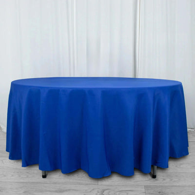 Round blue table with draped tablecloth on a plain backdrop.