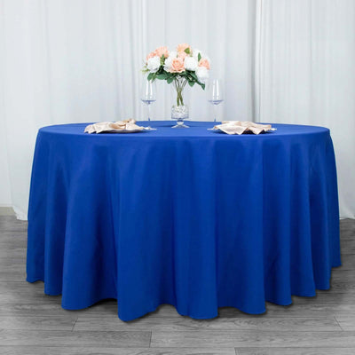 Round blue tablecloth with elegant floral centerpiece and glassware.