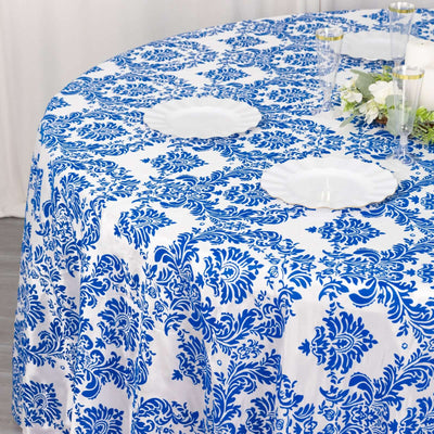 Blue floral tablecloth draped over a round table with white plates.