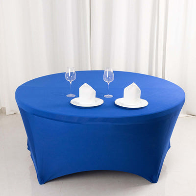 Round blue table with white plates and glasses on a plain backdrop.