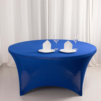 Blue tablecloth draped on an oval table set with plates and glasses.