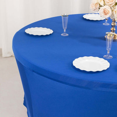 Round blue table with white scalloped plates set for dining.