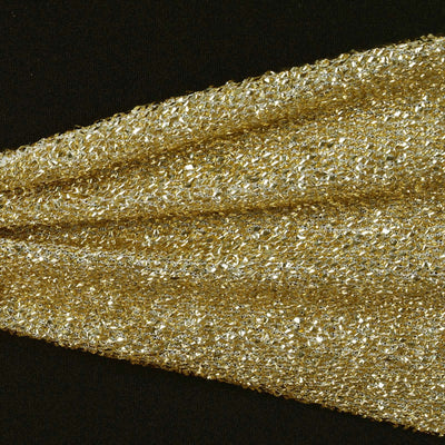 Shimmering gold textured fabric draped elegantly on a black background.