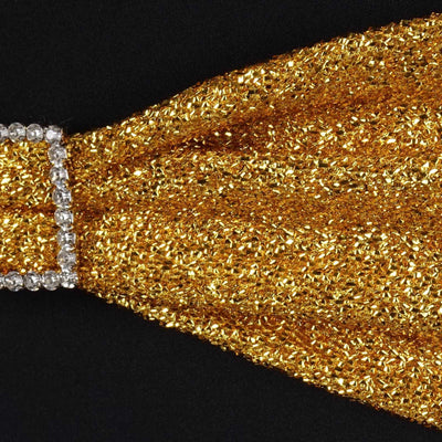 Gold glitter fabric close-up with rhinestone detail.