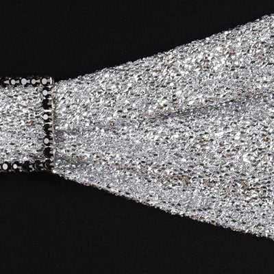 Silver sequin fabric with black embellishments, ideal for fashion design.