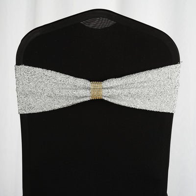 Silver glitter chair sash with gold embellishments on a black chair.