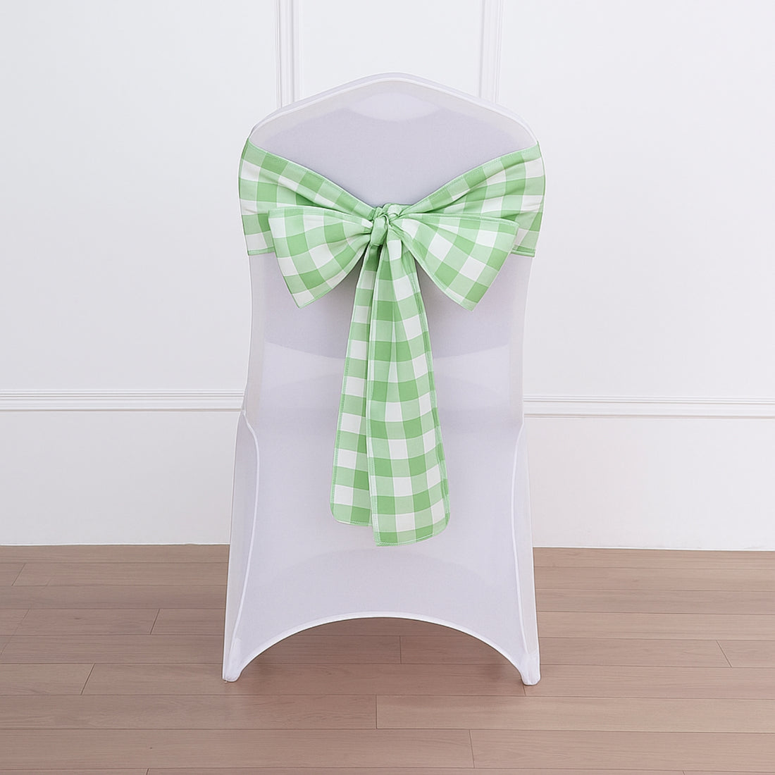 Green checkered chair sash on a white chair against a plain backdrop