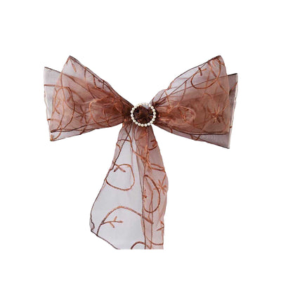 Brown sheer ribbon bow with pearl embellishment on a plain backdrop