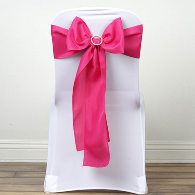 Pink satin chair bow with jewel accent on white chair.