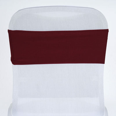 Burgundy chair cover sash on a white chair against a plain backdrop