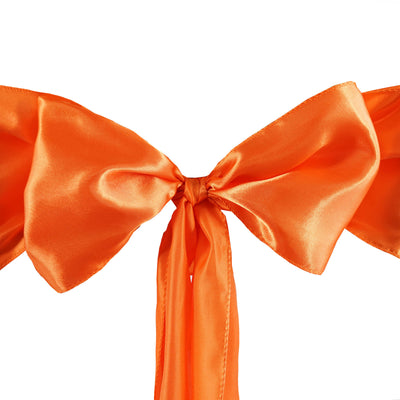 Orange satin ribbon bow with long tails for decorating gifts and crafts.
