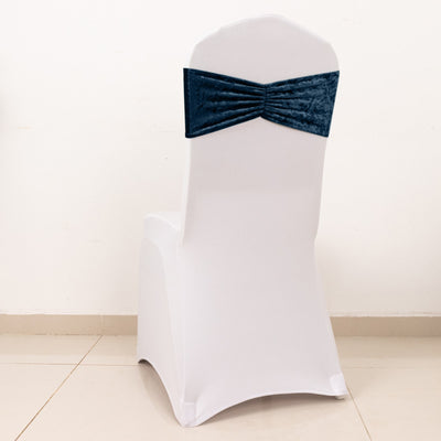 White chair cover with a navy blue velvet bow on the back.