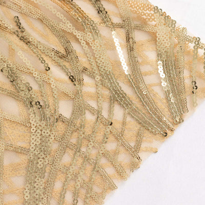 Gold sequin fabric with intricate patterns on a light background.