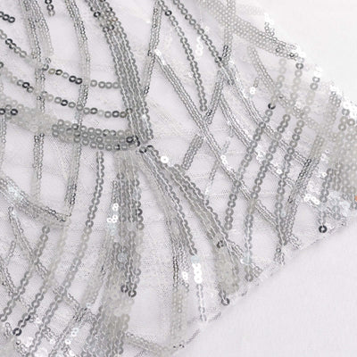 Silver sequin fabric with a wavy pattern on a white backdrop.