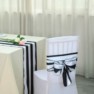 Elegant white chair cover with black and silver ribbon on a decorated table.