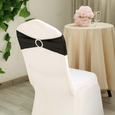 Black chair cover with decorative buckle on a white chair in a styled setting.