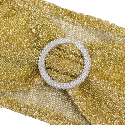 Gold textured fabric with a clear circular embellishment.