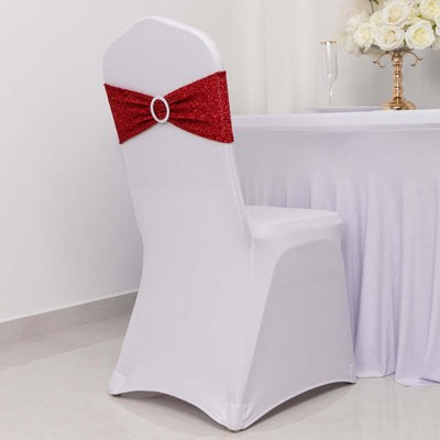 White chair with red sequined bow on a plain backdrop.