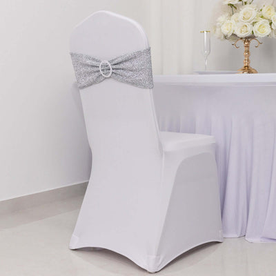 White chair cover with silver glitter bow, elegantly styled for events.