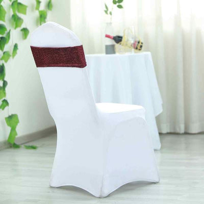 White chair cover with burgundy sash in a bright, elegant setting.
