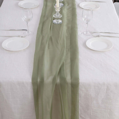Elegant green table runner on a white table setting with glassware and plates.