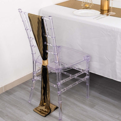Clear acrylic chair with black and gold ribbon, styled for an elegant dining setup.