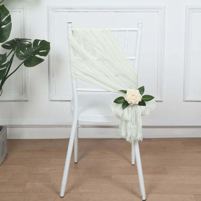 Elegant white chair with draped fabric and floral decoration.