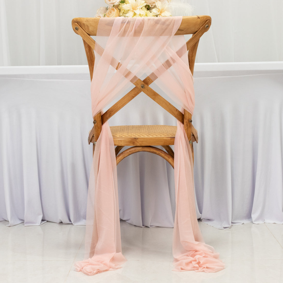 Peach chiffon chair sash draped elegantly over a wooden chair.