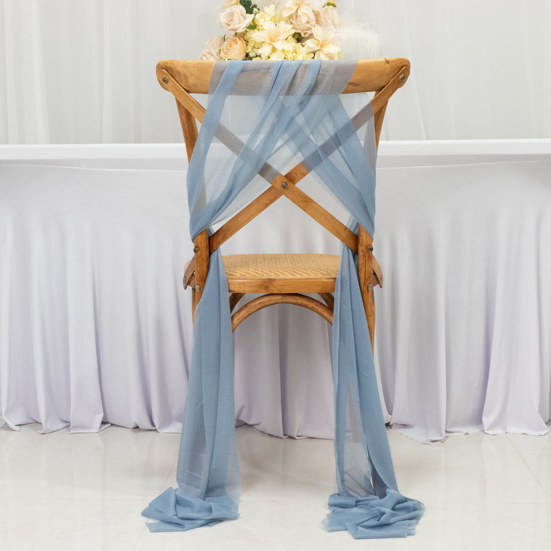 Wooden chair with blue fabric draped elegantly, styled for a wedding or event setting.