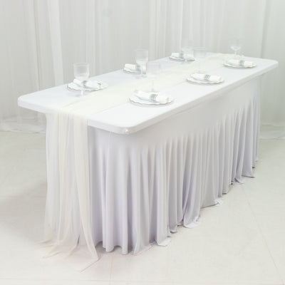 White tablecloth draped on a table set for dining with glasses and napkins.