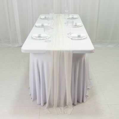 Elegant dining table set with white linens and glassware in a studio setting.