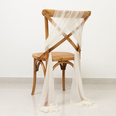 Elegant cream chiffon draped on a wooden chair against a plain background.
