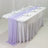 Elegant table setup with lavender draping and glassware for events.