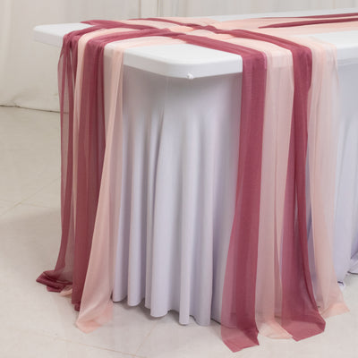 Sheer table runners in shades of pink and burgundy draped over a white table.