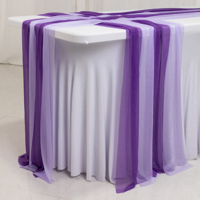 Purple sheer table runners draped elegantly over a white table.