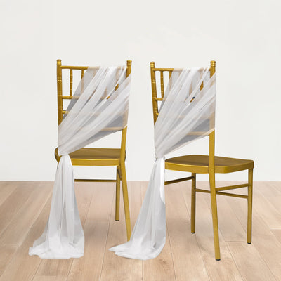 Gold chiavari chairs draped with white sheer fabric in a studio setting.