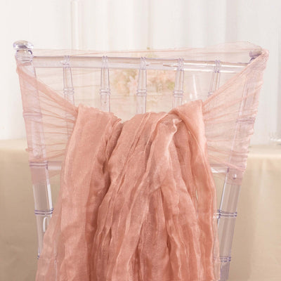 Peach satin chair sash draped elegantly over a transparent chiavari chair.