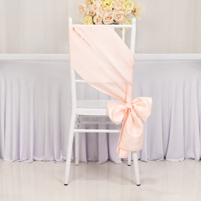 Peach chair sash tied in a bow on a white chair with floral arrangement