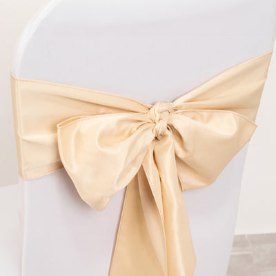 Gold satin chair sash bow tied on a white chair.